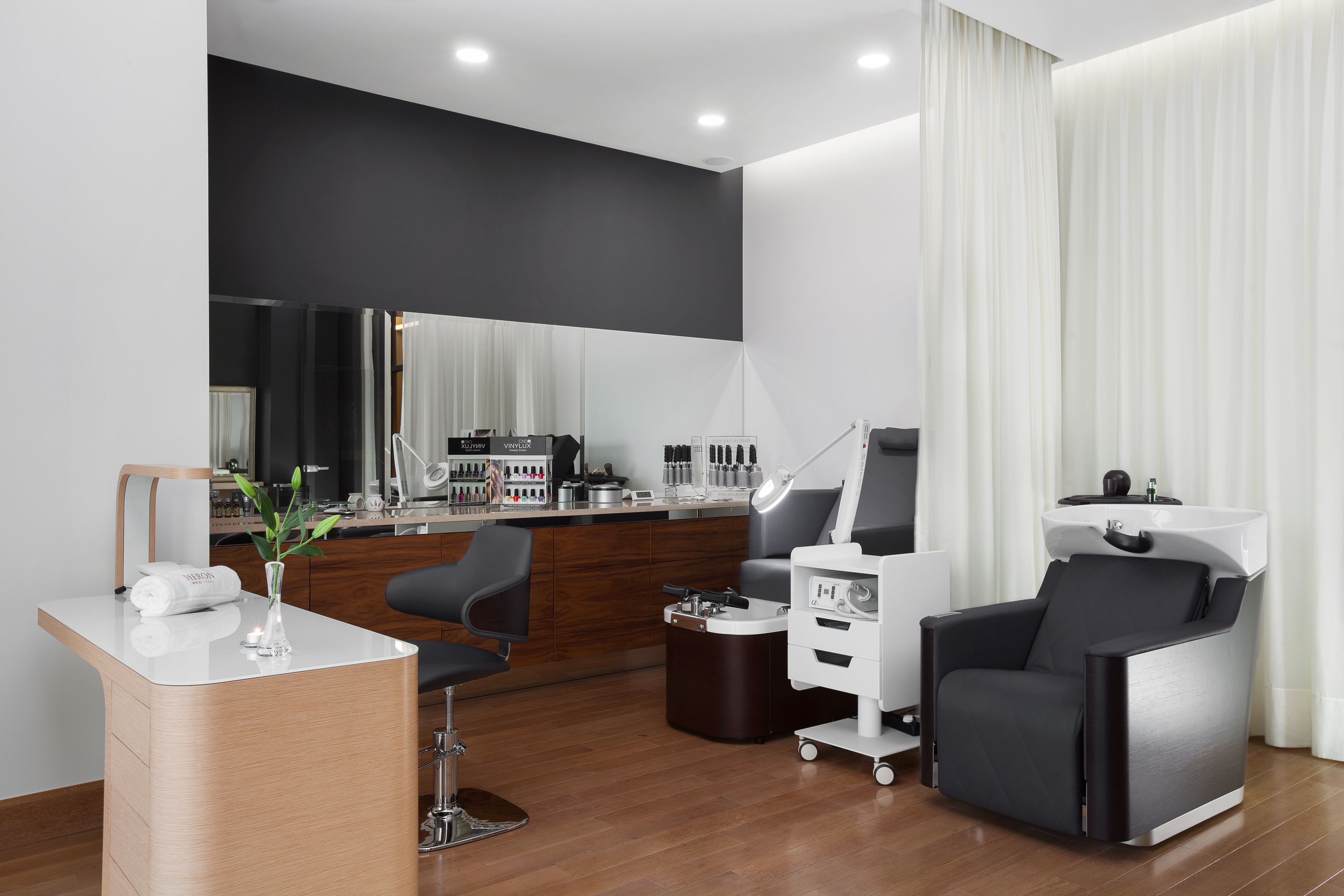 Un salón moderno con mostrador de recepción, sillón de masajes y un espejo grande.
