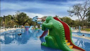 A water park with a large green dinosaur slide and a blue water slide in the background. - Hotel Internacional Gravatal (Gravatal)
