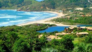 A coastal area with a beach, a small body of water, and houses with thatched roofs. - Hotel Internacional Gravatal (Gravatal)