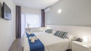 A hotel room with a large bed, a bedside table with a phone, a TV mounted on the wall, and an air conditioning unit. - Hotel Victoria (Lloret de Mar)