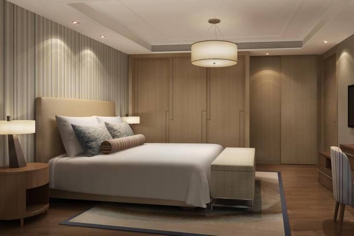 Un dormitorio moderno con una cama grande, lámparas de noche, un televisor y un escritorio de madera.