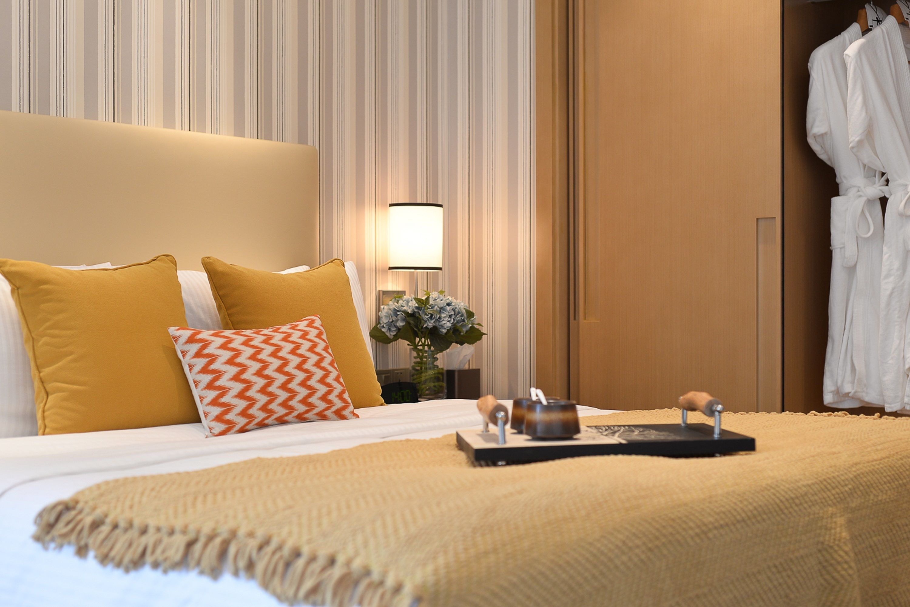 Una habitación de hotel con una cama, una mesita de noche con lámpara y una bata colgada en la puerta.