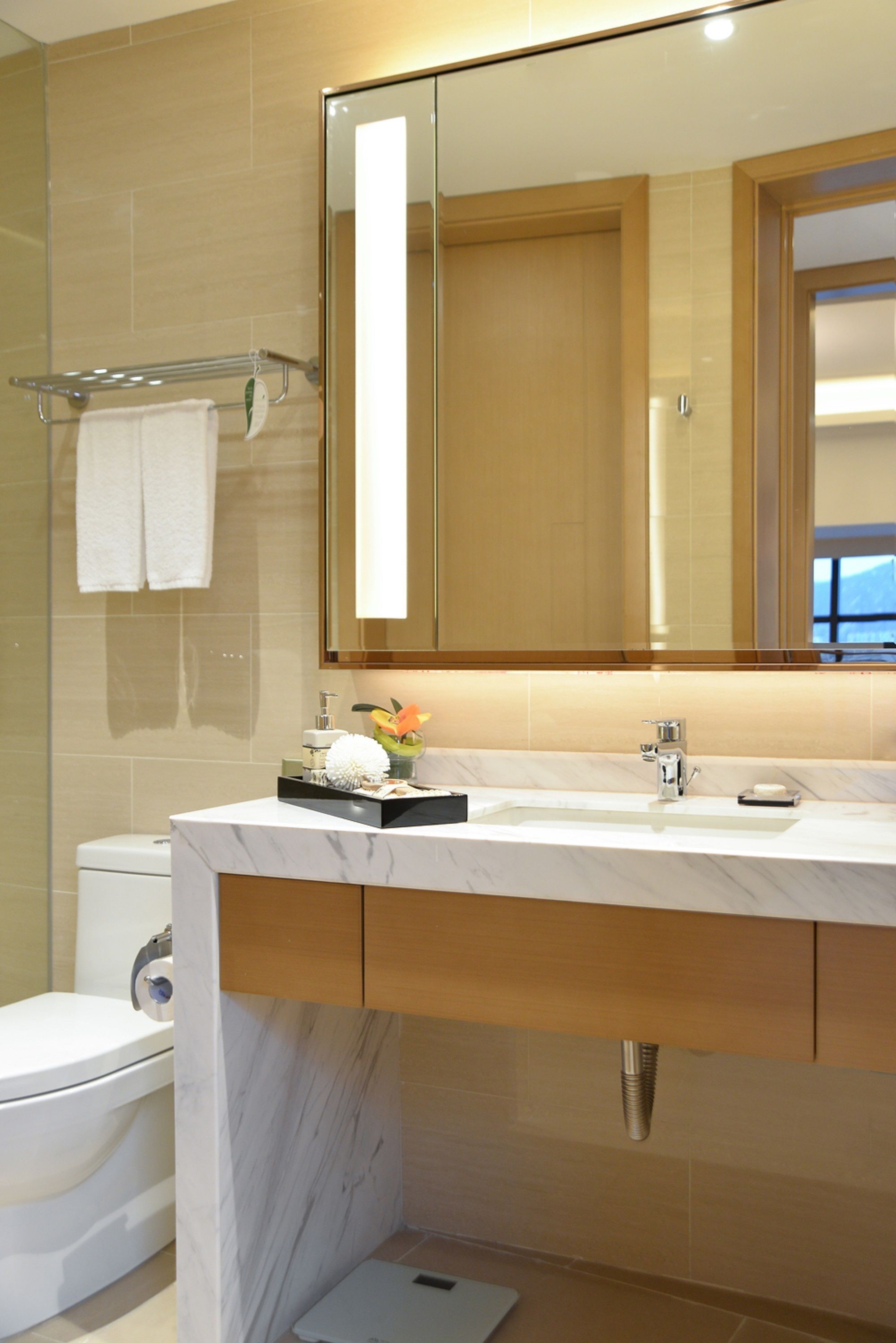 A modern bathroom with a marble sink, a large mirror, and a toilet.