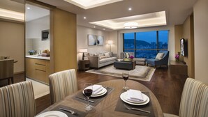 Ein modernes Hotelzimmer mit Essbereich, einem Wohnzimmer mit Blick auf die Stadt und einer Küche.
