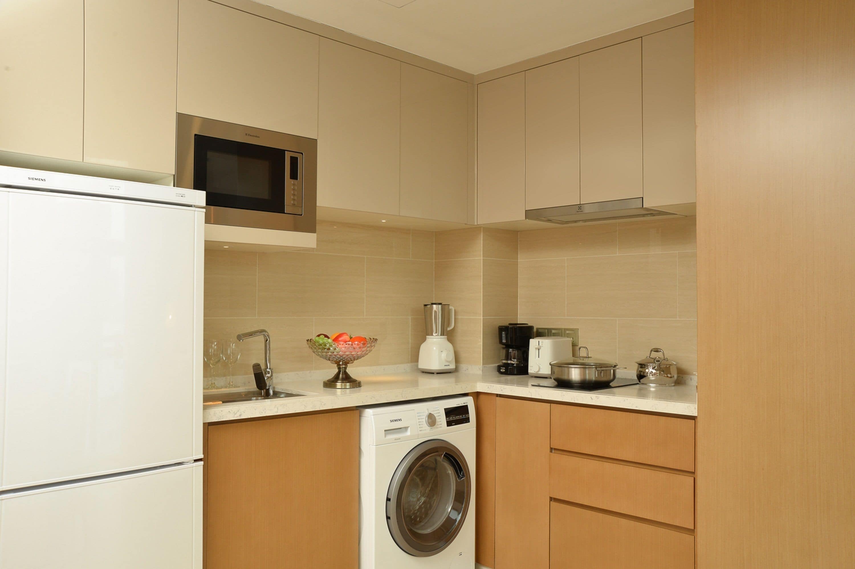 A compact kitchen with a built-in washing machine, a microwave, and a coffee maker.
