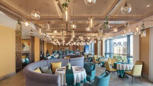 Ein modernes Restaurant mit runden Tischen, bequemen Sitzgelegenheiten und hängenden Pendelleuchten.