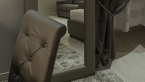 A modern room with a large mirror, a tufted chair, a sofa, and a lamp. - Fabio Massimo Guest House (Rome)