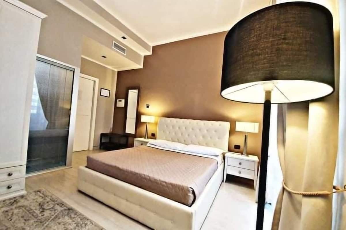 Une chambre à coucher avec un lit, des tables de chevet, une lampe et une armoire.
