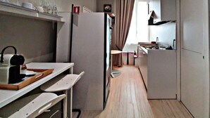 A compact kitchen with a refrigerator, a sink, and a dining area with a table and chairs. - Fabio Massimo Guest House (Rome)
