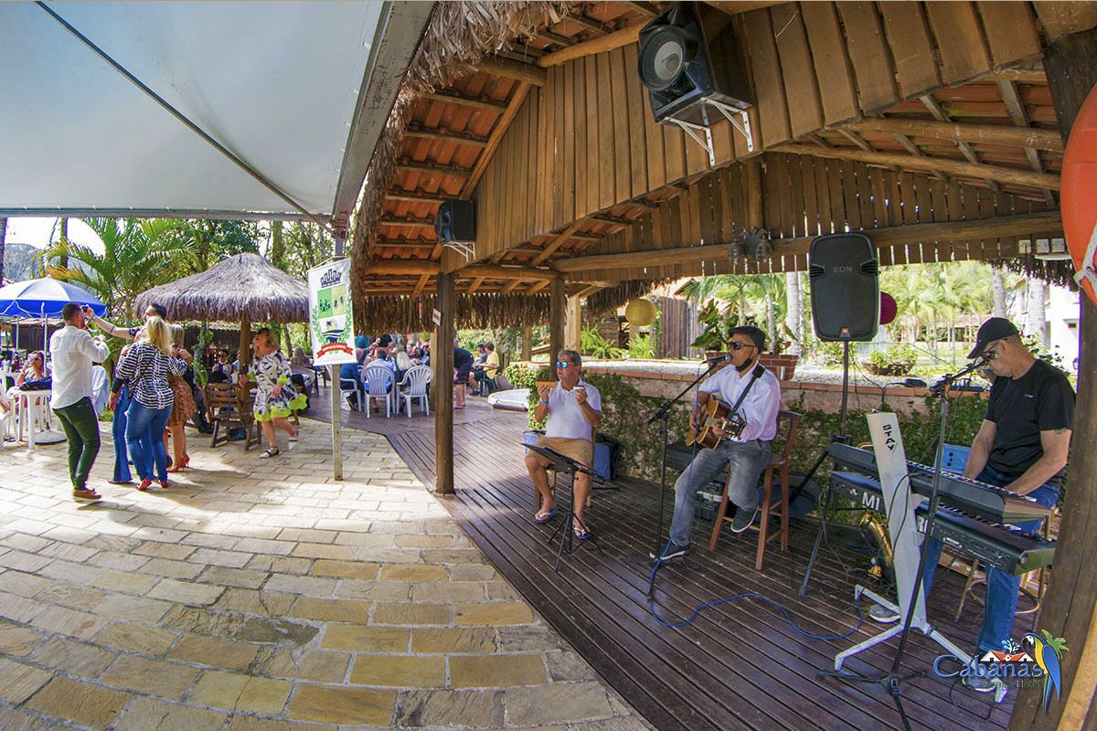 Un espacio al aire libre con una terraza de madera, un techo de paja y un escenario con instrumentos musicales.