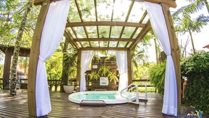A wooden gazebo with a glass roof, a hot tub, and surrounding lush greenery. - Cabanas Termas Hotel (Gravatal)