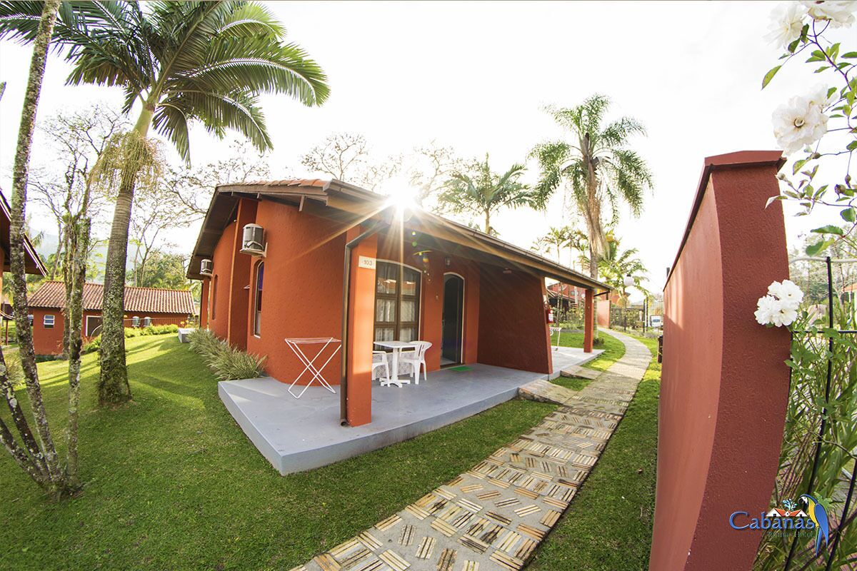 A red building with a patio, white furniture, and palm trees.