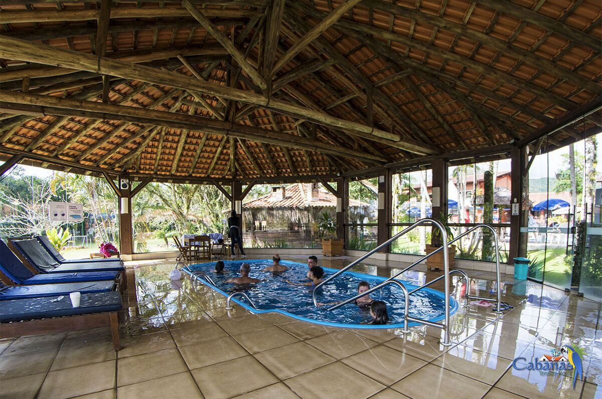 Zona de piscina cubierta con sillones de descanso y bar junto a la piscina.