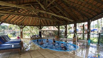 Zona de piscina cubierta con sillones de descanso y bar junto a la piscina.