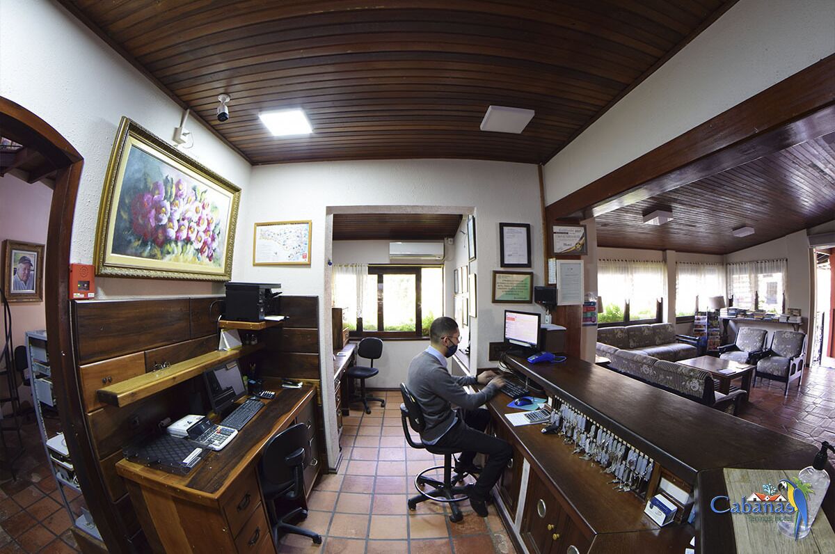 A hotel office with a wooden desk, computer, and a bar area with seating.