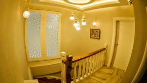 A staircase with a wooden handrail, a ceiling light fixture, and a wall-mounted light. - Hatunca Otel & Restaurant (Amasya)