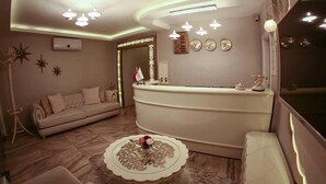 A modern reception area with a curved desk, a sofa, and a decorative coffee table. - Hatunca Otel & Restaurant (Amasya)