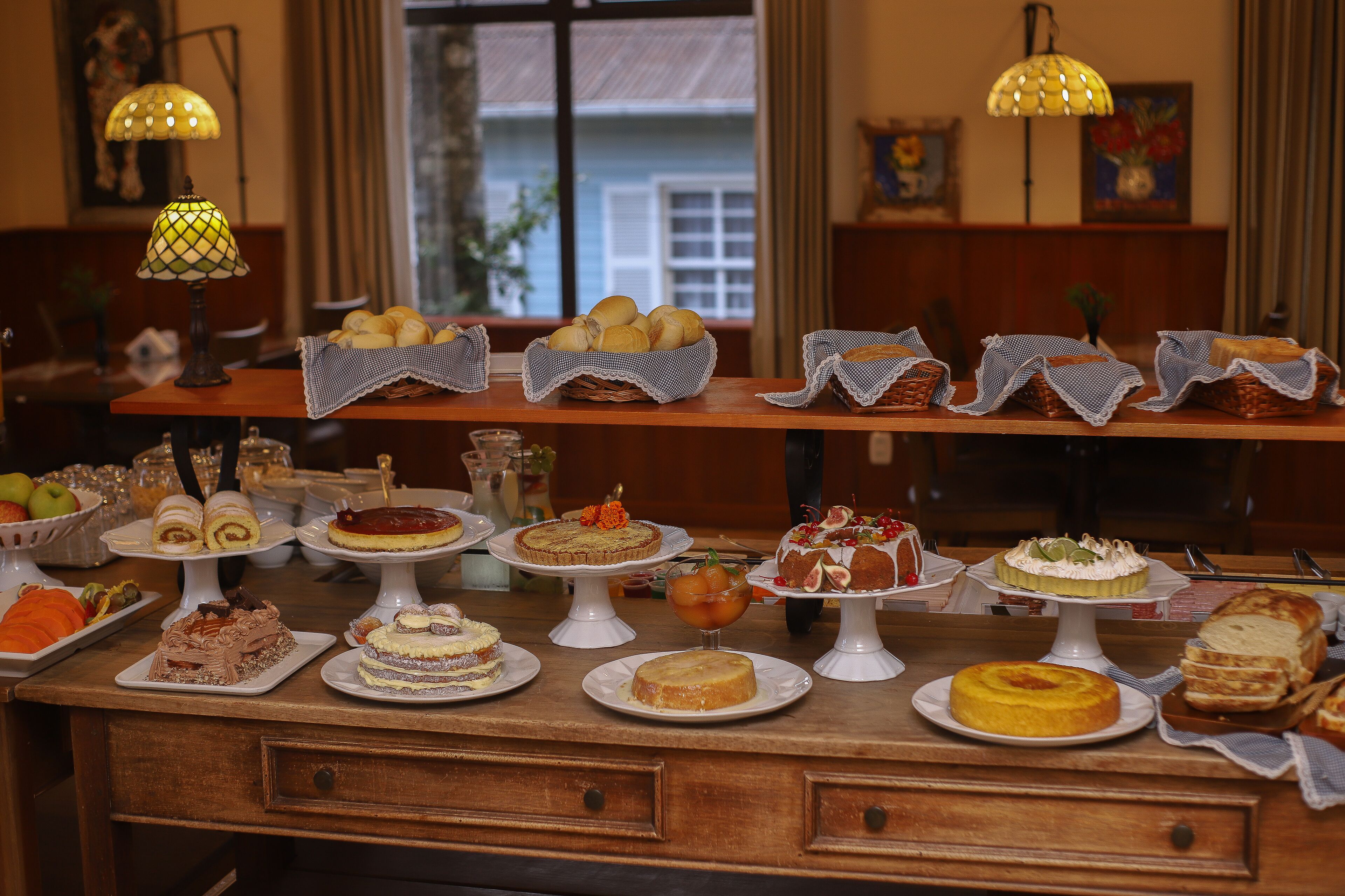 Uma mesa de buffet com diversos doces e cestas de pão.