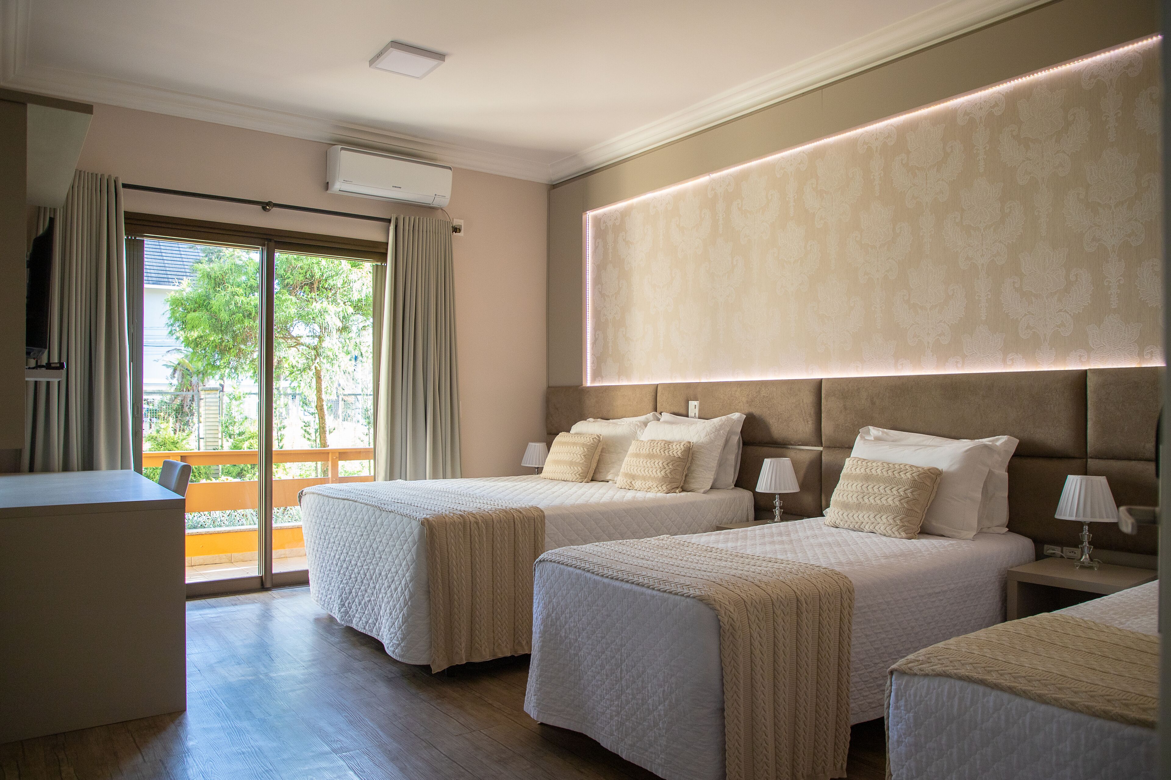 Une chambre d’hôtel avec deux lits, un bureau et une grande fenêtre avec des rideaux.