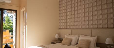 A bedroom with a large bed, a padded headboard, two bedside tables with lamps, and a sliding glass door leading to an outdoor area.
