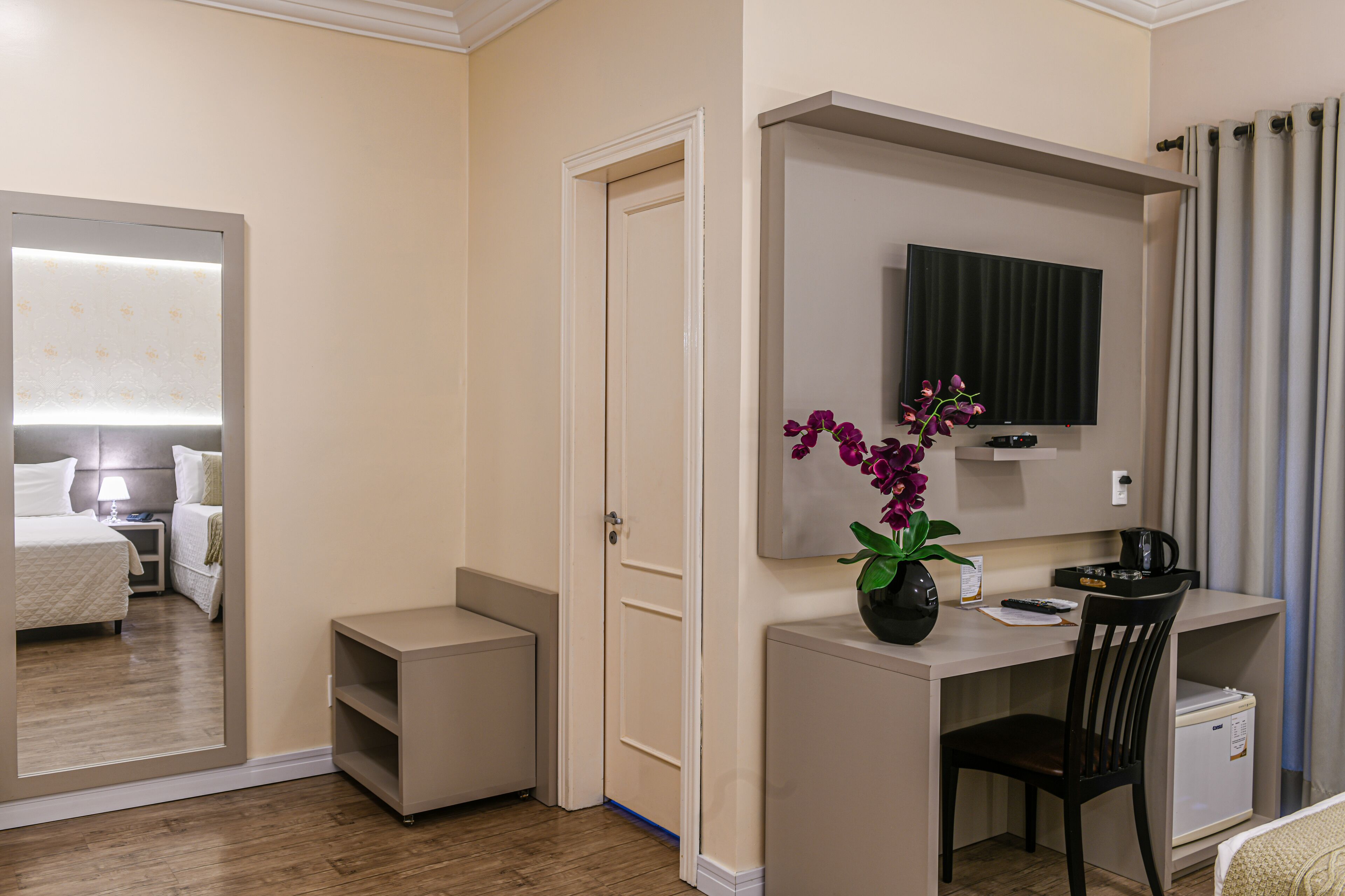 A hotel room with a bed, a desk, a chair, a TV, and a small cabinet.