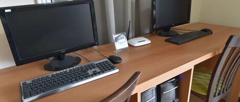 A wooden desk with two monitors, a keyboard, and a mouse.