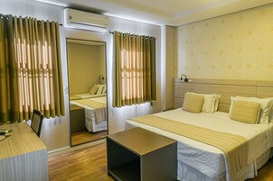 Una habitación de hotel con cama, mesitas de noche, escritorio y aire acondicionado.