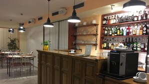 A bar area with a wooden counter, bar stools, and a variety of liquor bottles.