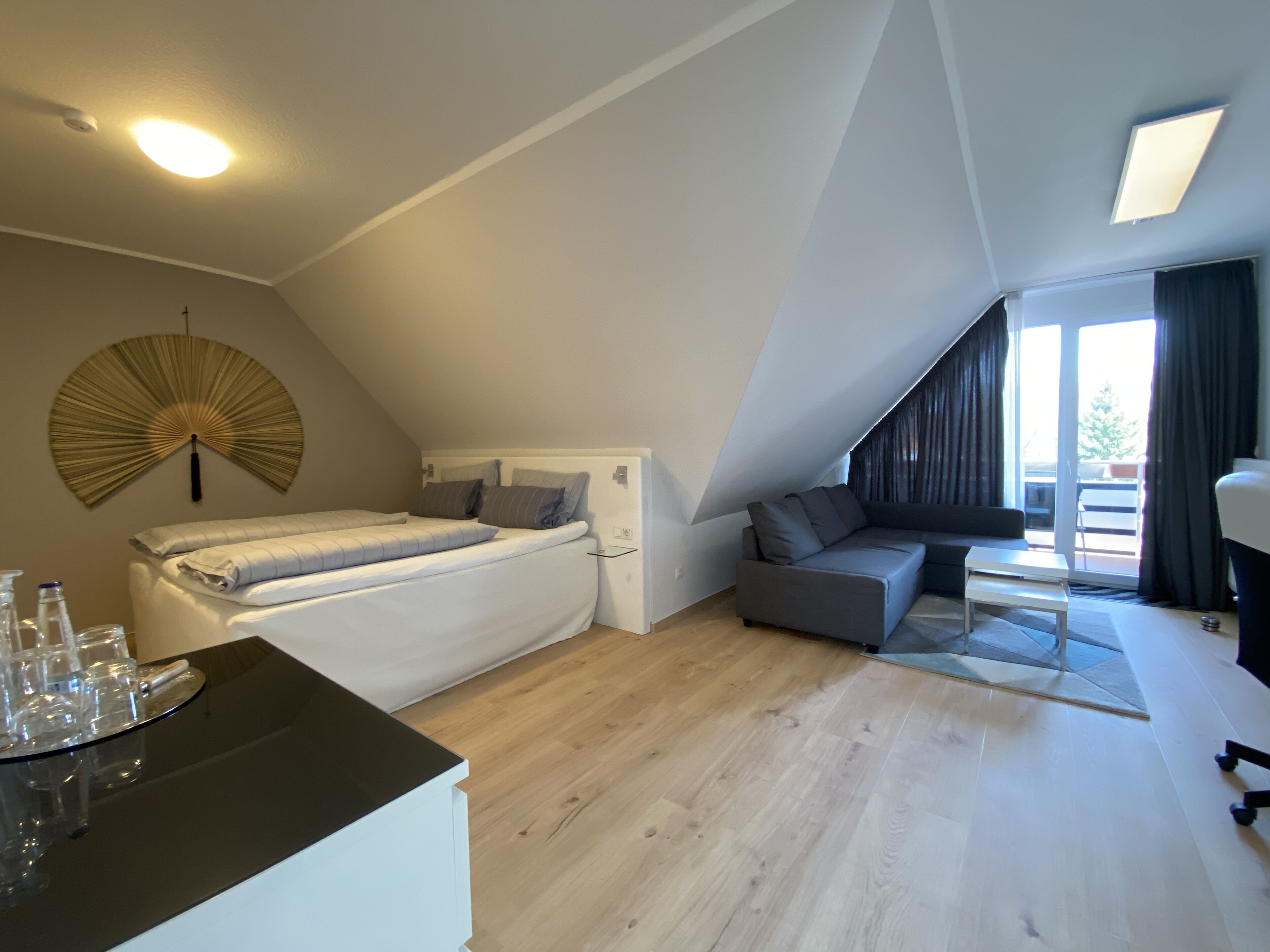 A modern loft bedroom with a bed, a sofa, and a dining table.