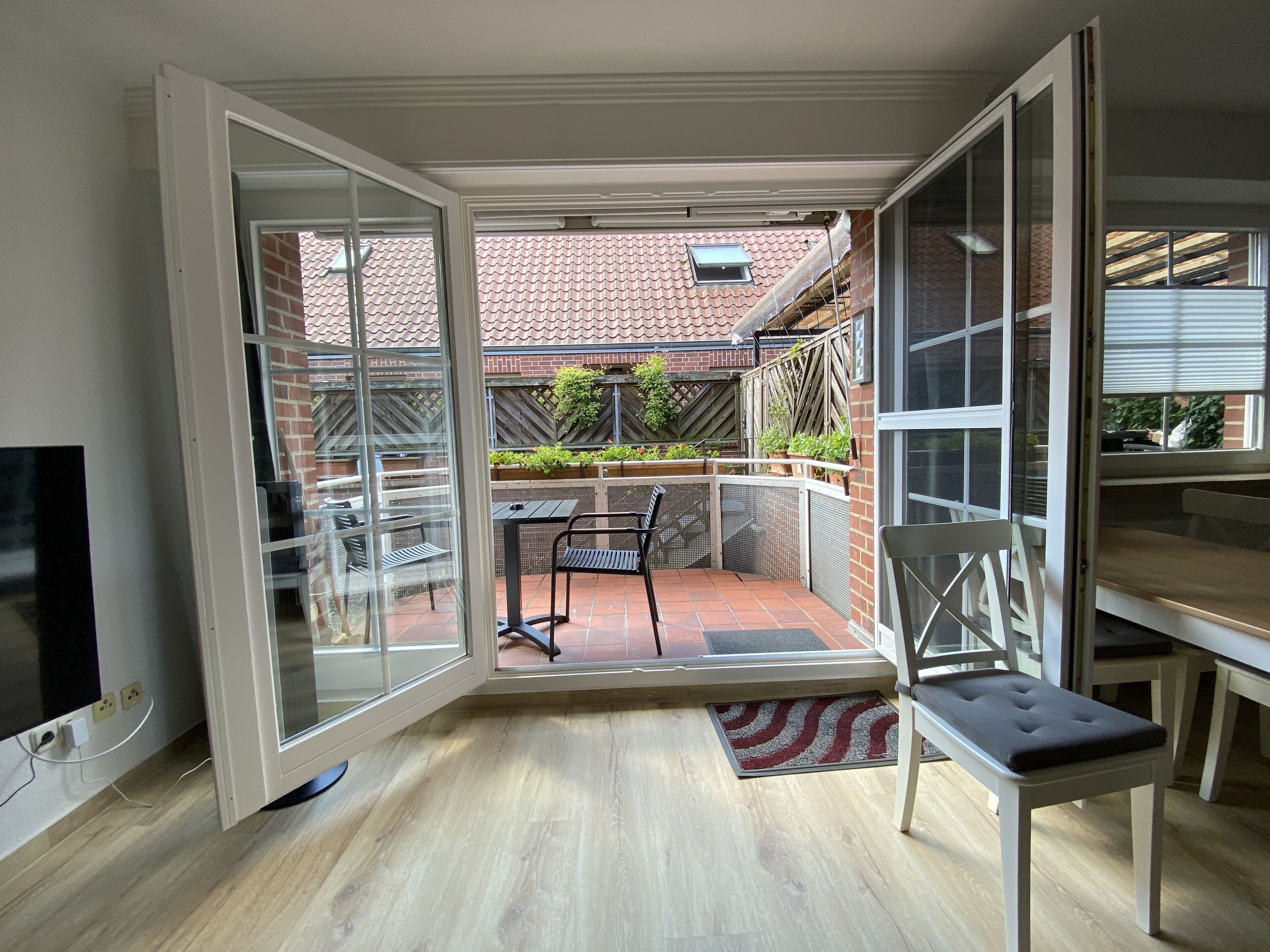Una habitación con una puerta corrediza de vidrio que da a un patio al aire libre con una mesa y sillas.