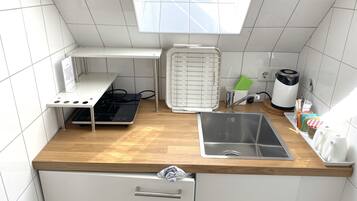 Una cocina compacta con estufa integrada, un lavamanos y un ventanal sobre la encimera.