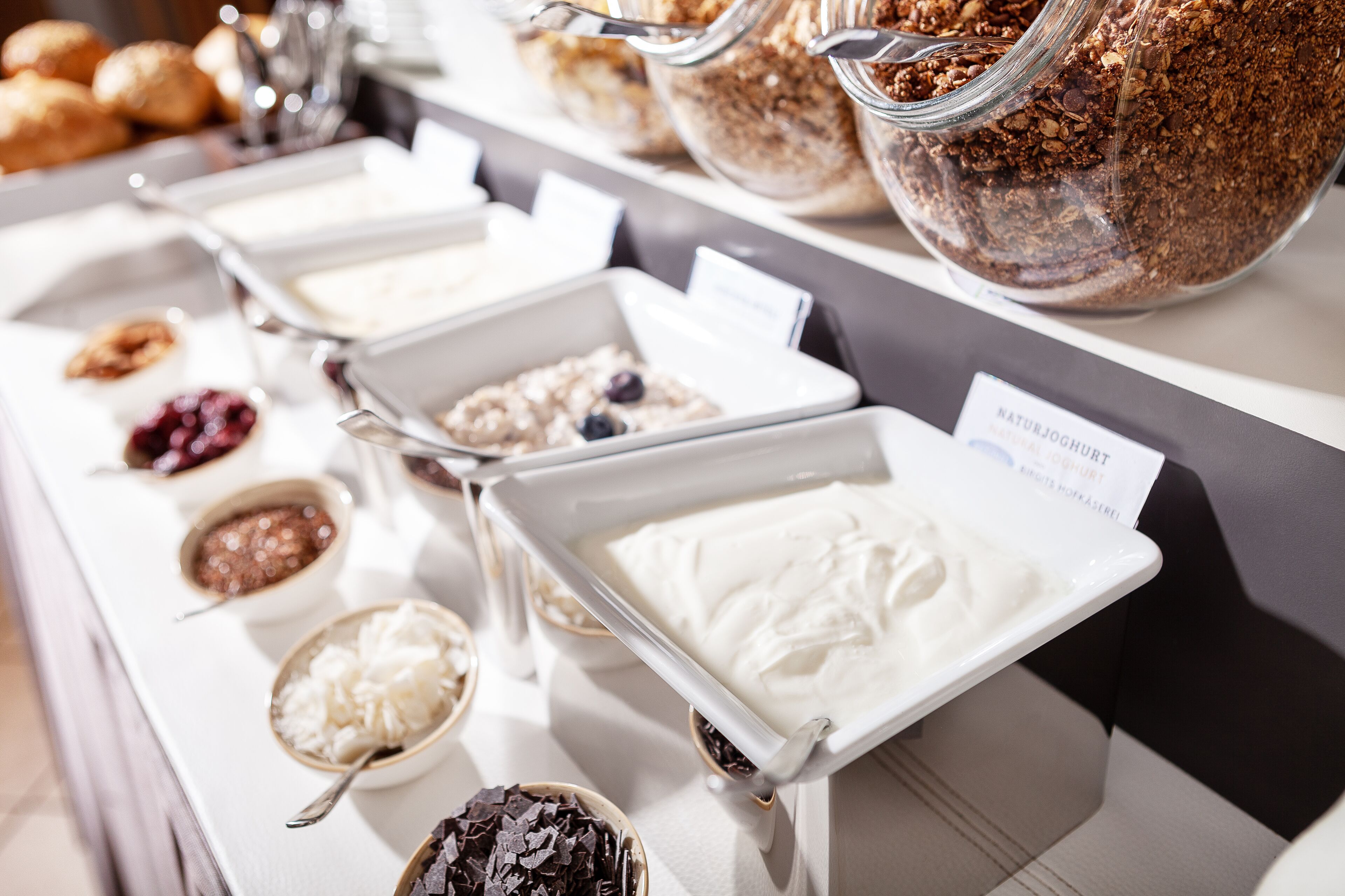 Ein Buffet mit verschiedenen Speisen, darunter Obst, Müsli und Desserts.