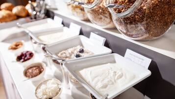 Ein Buffet mit verschiedenen Speisen, darunter Obst, Müsli und Desserts.
