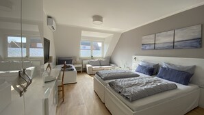 A modern bedroom with a large bed, a desk, and a TV. - Hotel zur Bever (Telgte)