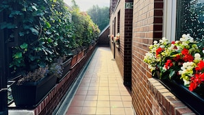 A narrow brick corridor with a tiled floor, a brick wall on one side, and a window on the other. - Hotel zur Bever (Telgte)