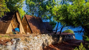 A stone wall with a tent and a wooden structure near a body of water. - Cast Away - Eco Village (Jelsa)