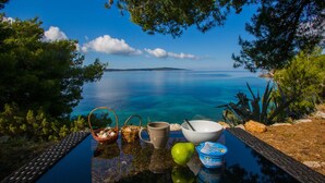 A table with breakfast items and a view of a calm sea and distant land. - Cast Away - Eco Village (Jelsa)