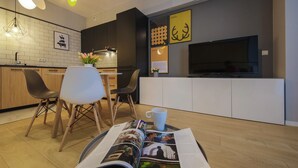 A modern kitchen with dark cabinetry, a white countertop, and a large flat-screen TV mounted above it.