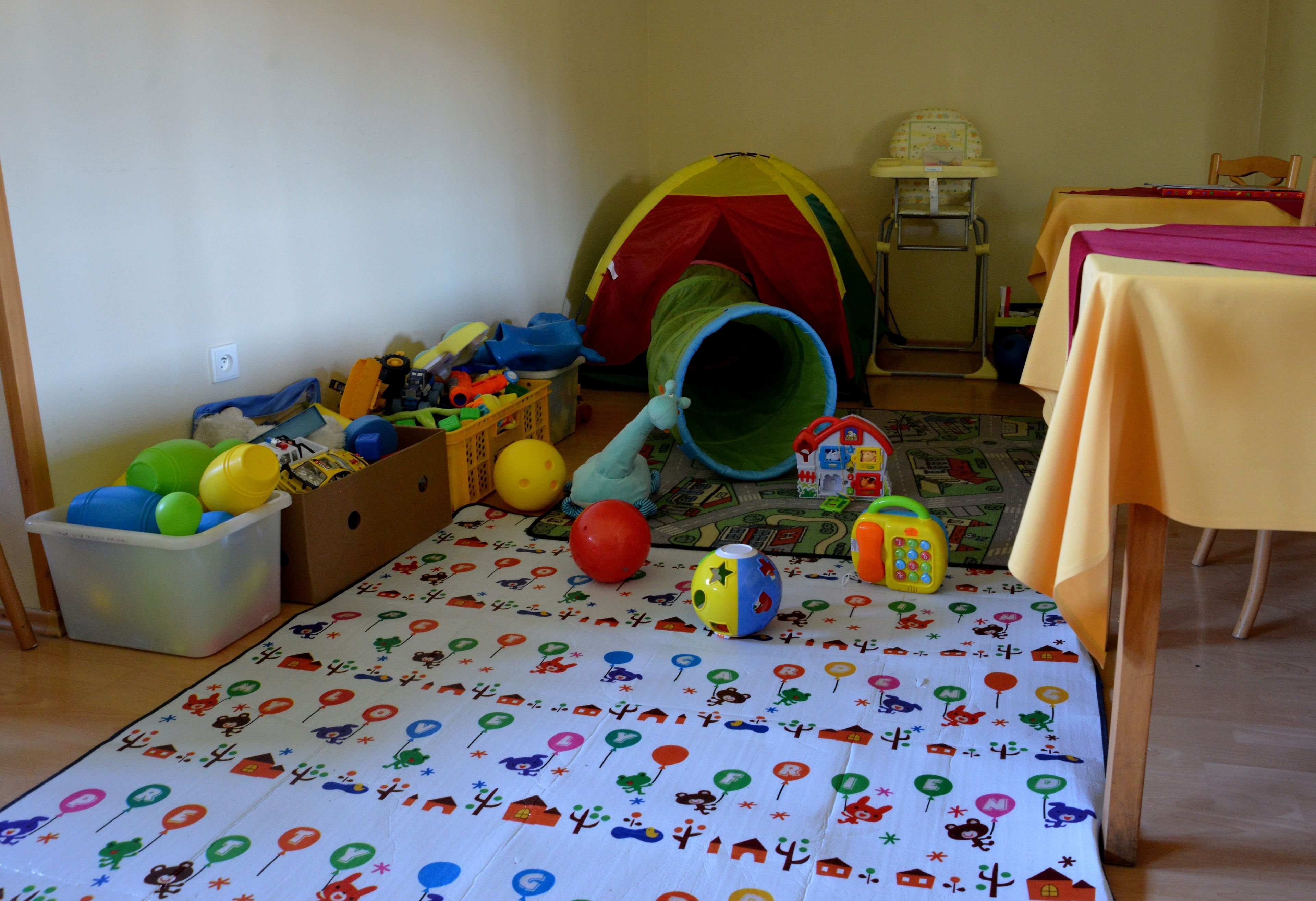 Una sala de juegos con una carpa, juguetes y un tapete de colores.