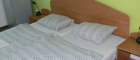 A neatly made bed with patterned bedding, a wooden headboard, and a small bedside table with a lamp.