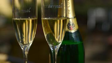 Dos copas de champán llenas de burbujas y una botella con la etiqueta 'Hubert De Luxe' sobre una mesa.