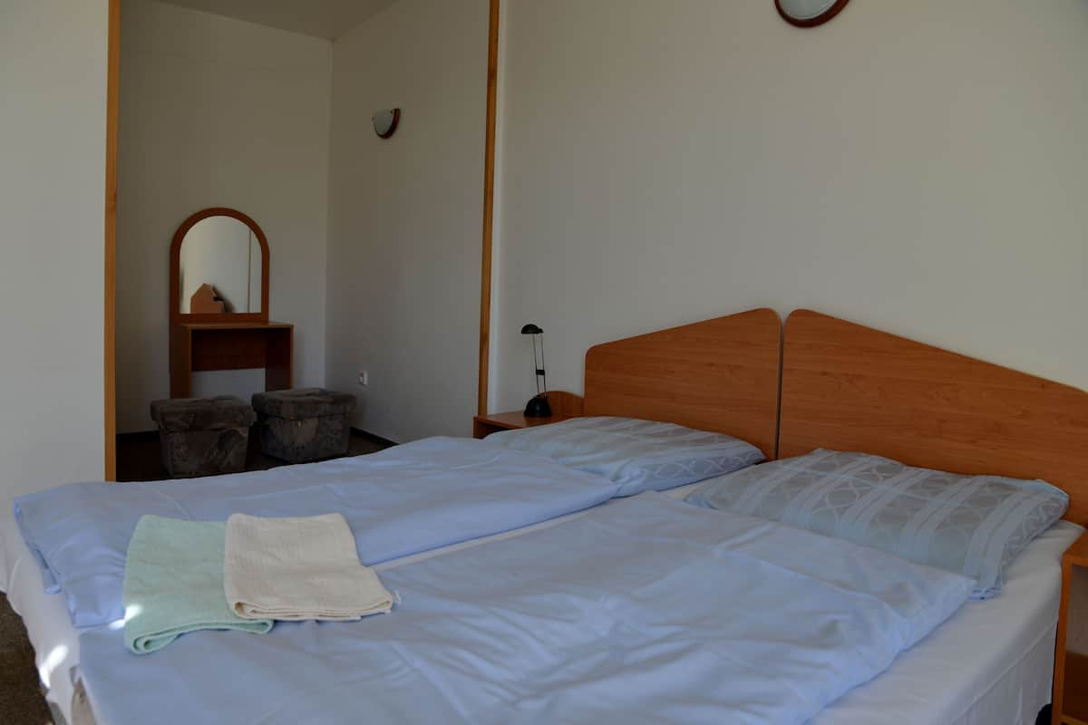 Una cama doble con ropa de cama azul claro, un cabecero de madera y una mesita de noche pequeña con una lámpara.