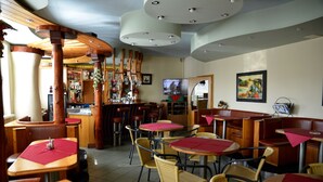 Un restaurante con mesas y sillas de madera, una zona de bar y una pantalla de televisión.