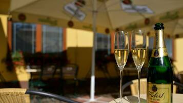 A bottle of Huber de Luxe champagne and two glasses on a table outdoors.