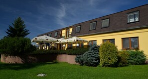 Un hôtel à la façade jaune, doté de nombreuses fenêtres et agrémenté de parasols à l’extérieur.
