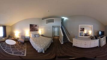 A bedroom with a bed, bedside tables, a dresser, a mirror, and a staircase.