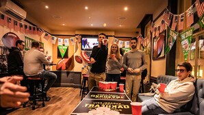 Une pièce avec une table de billard, des drapeaux américains et un écran de télévision.