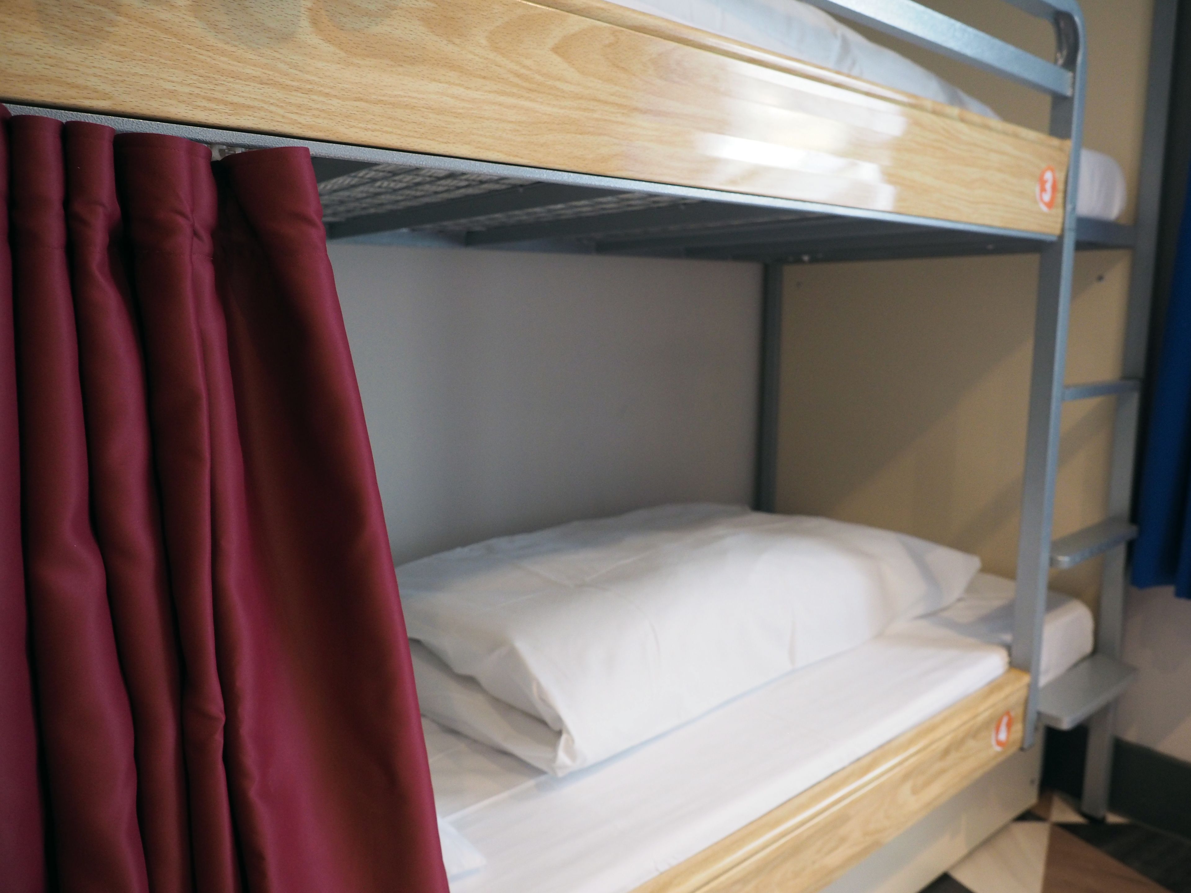 Una cama litera con estructura de madera y barandillas metálicas.