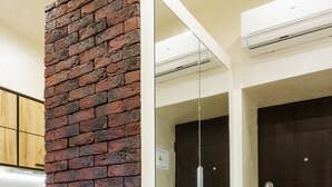 Una habitación con una pared de ladrillo decorativa, una puerta corredera de vidrio y una puerta de madera oscura.