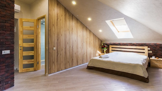 Un dormitorio con techo inclinado, armario de madera y tragaluz.